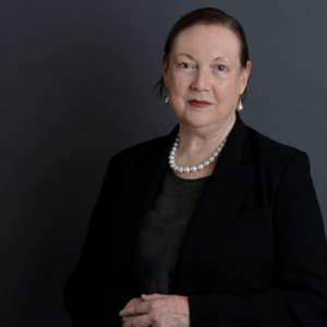 Lynne Gallagher standing in front of a navy background.