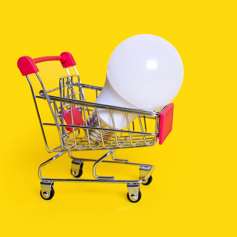 A miniature shopping trolley with a light bulb sitting in it.