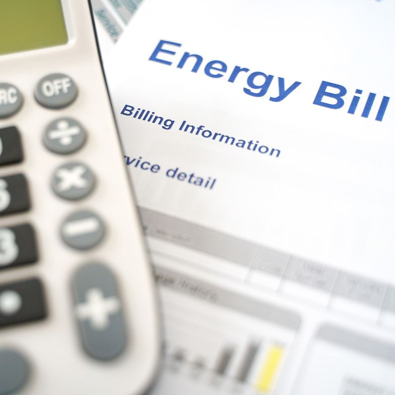An Energy Bill sitting on a desk with a calculator next to it.