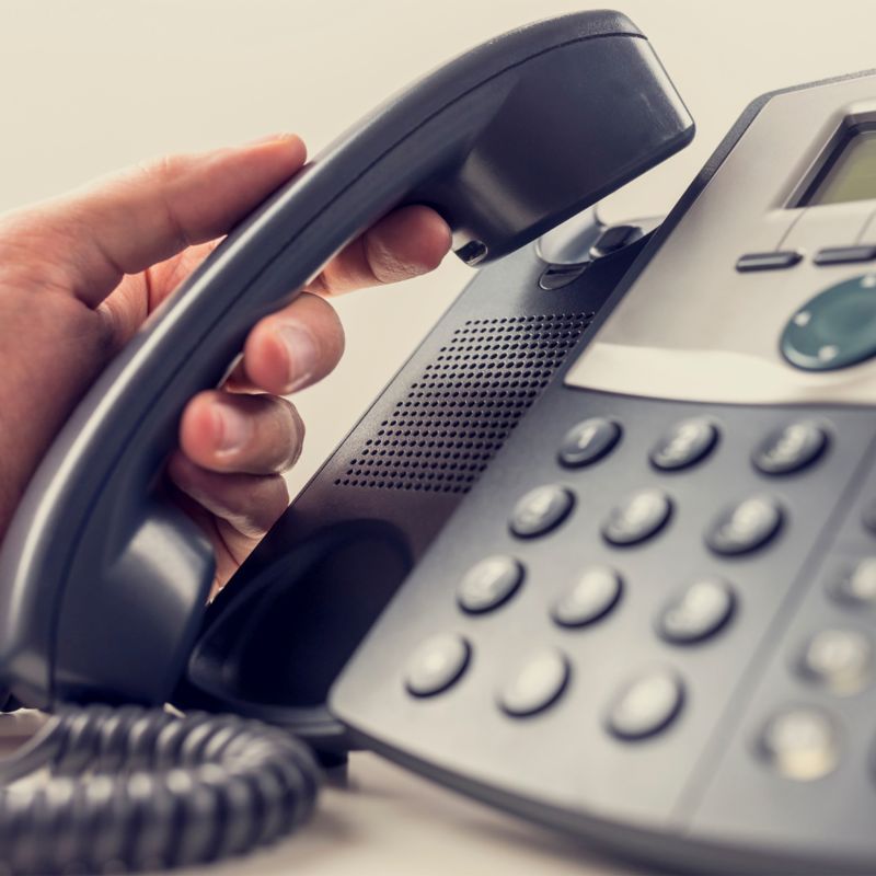 Close up of a person's hand as they pick up a landline telphone