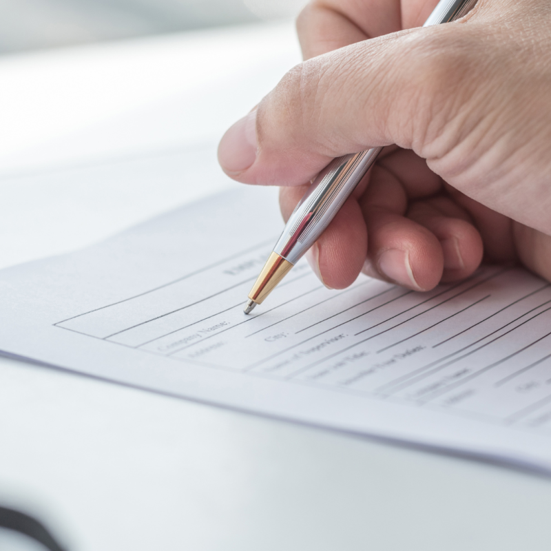 Close up of a hand holding a pen, writing on a piece of paper.