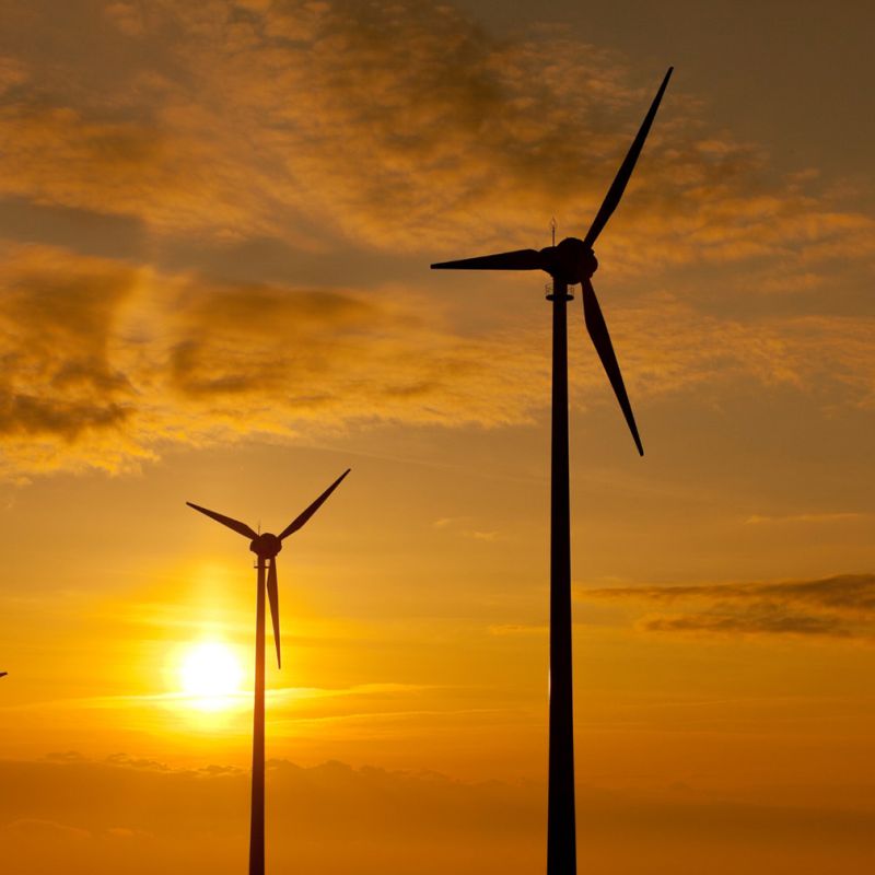 Wind turbines on a wind farm with the sun setting behind them