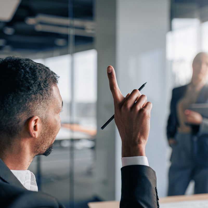 Man putting his hand up to speak during a business meeting