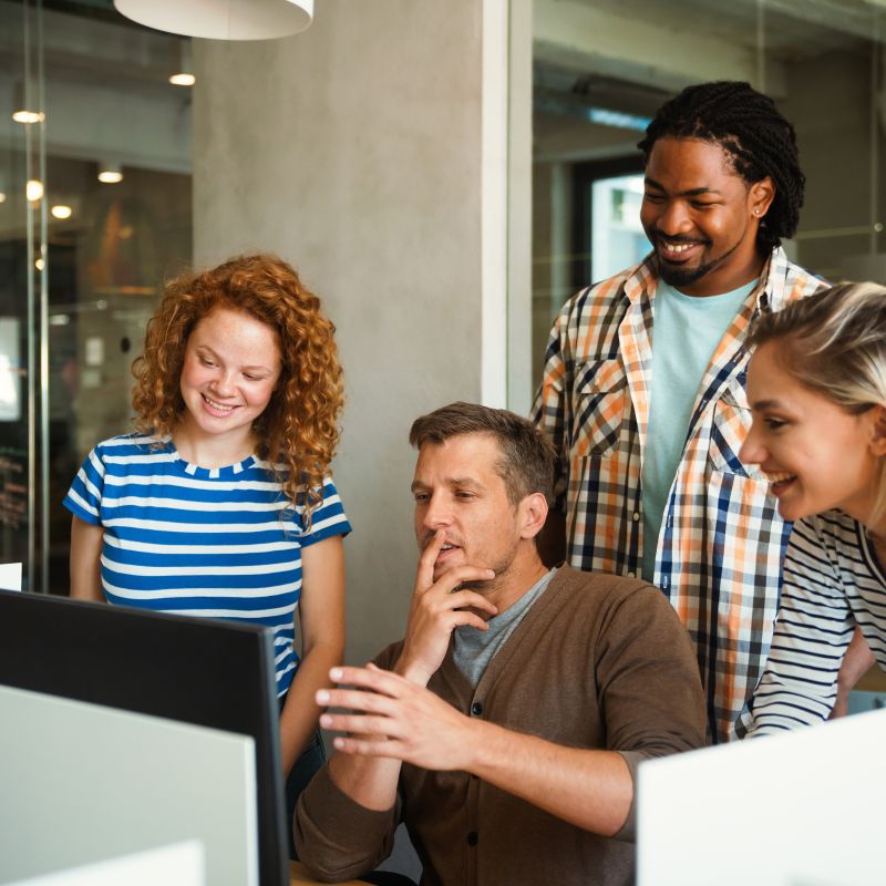 Three office workers looking at a computer screen