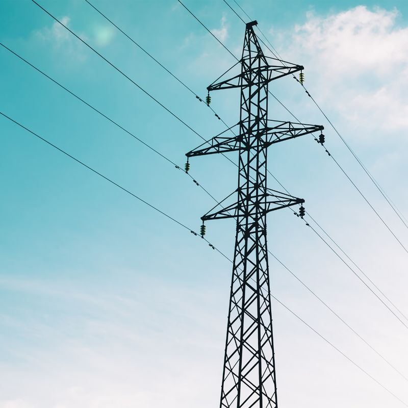 An electricity transmission tower with blue sky and clouds in the background