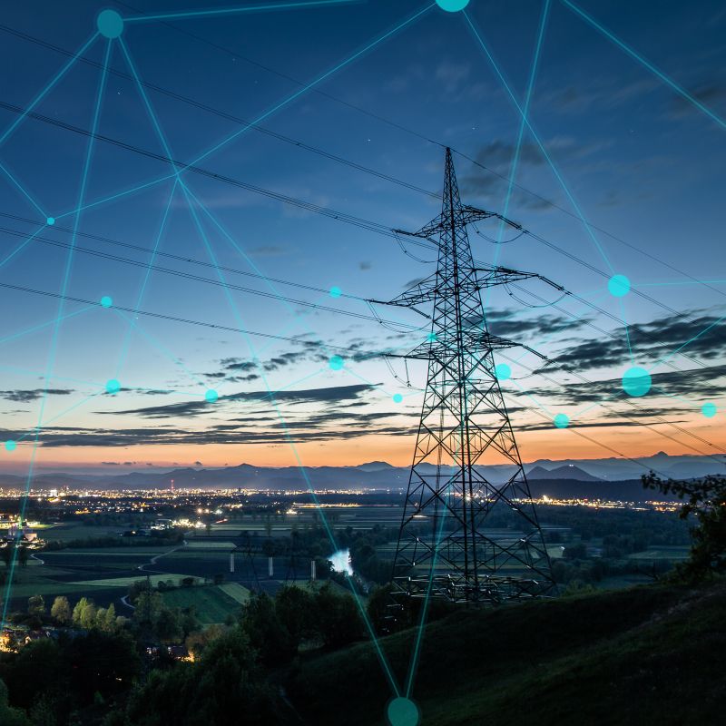 a tranmission tower with the lights of a city in the background with a graphical element of a grid sitting over the image.