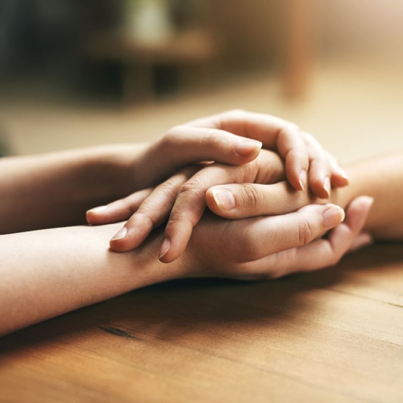 Two sets of hands clasping each other depicting support
