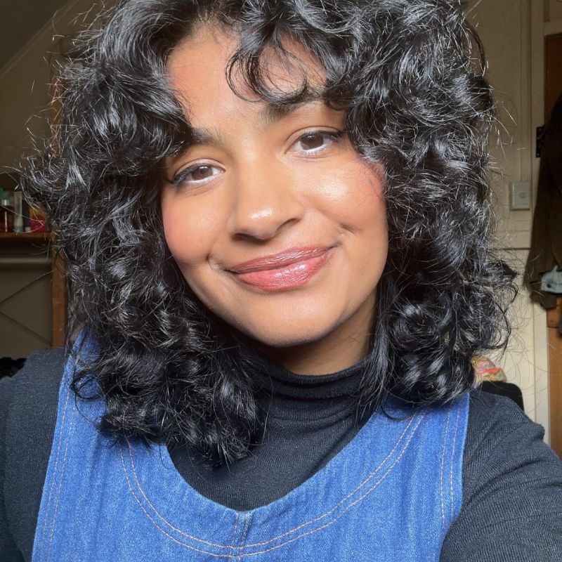 portrait of Assistant Director Prianka Thomas. She is wearing a blue top and smiling