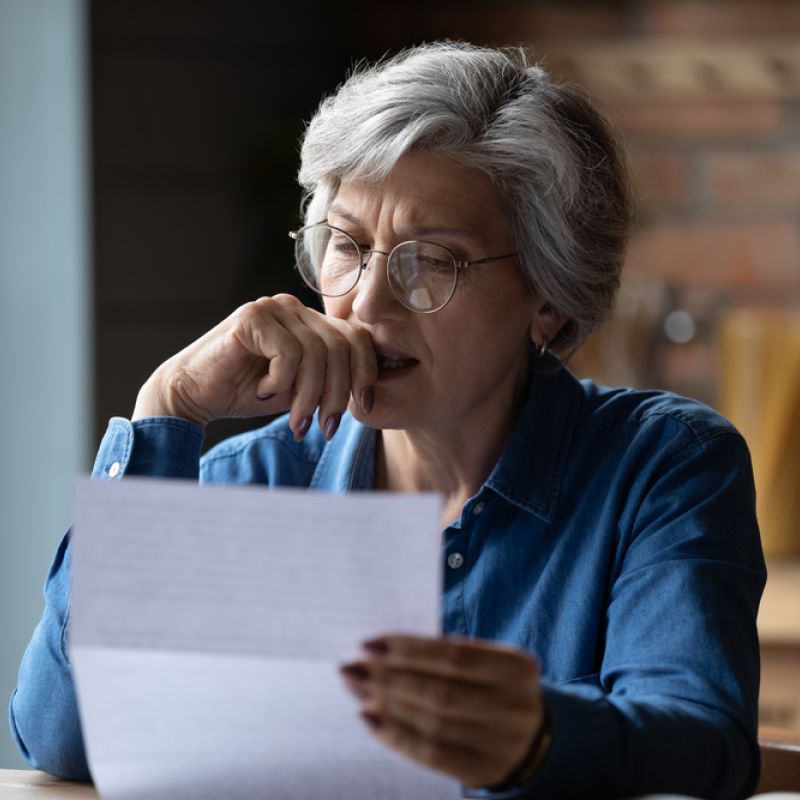 A woman holding an energy bill looking very concerned