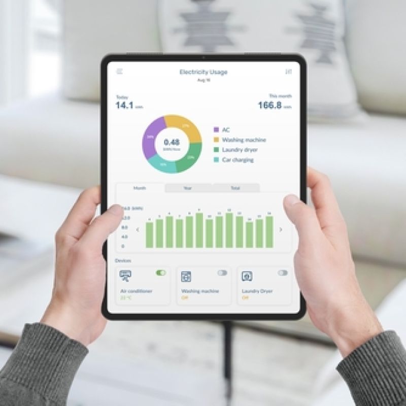 A woman holding a tablet that has data about her electricity usage on it