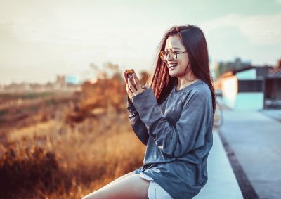 Woman sits outside looking at her phone