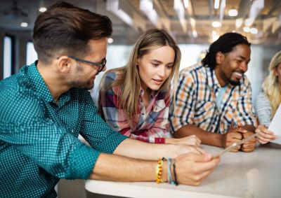 A group of four young colleagues collaborate while sitting around a table.
