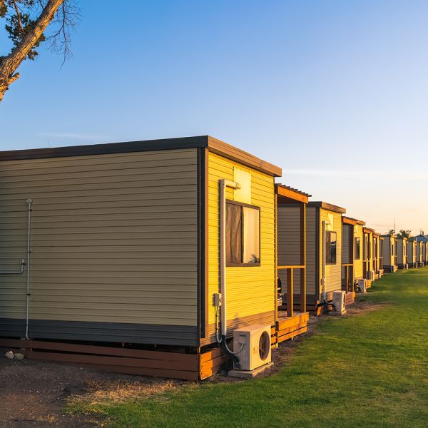 A row of cabins in a caravan holiday park with the sun setting in the background