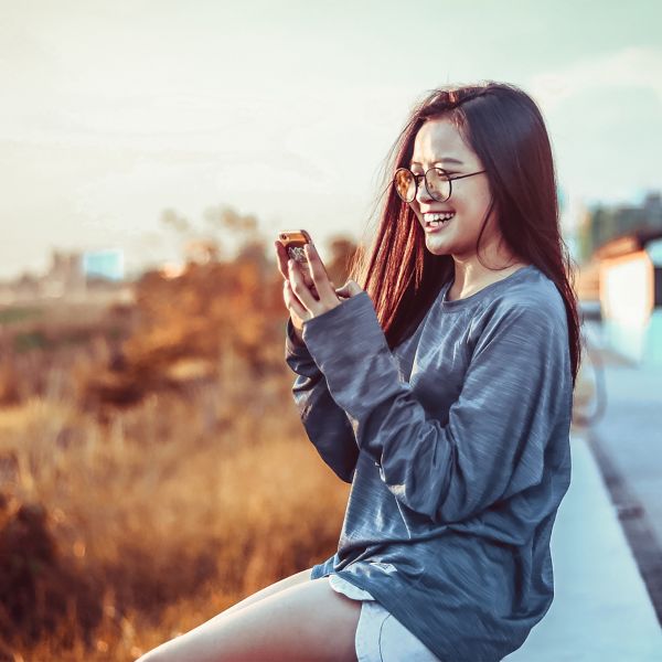 Woman sits outside looking at her phone