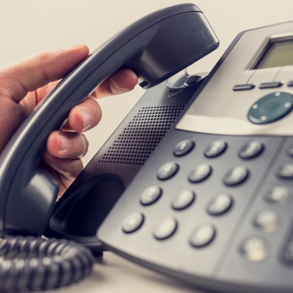 A person’s hand is holding a telephone headset, about to make a phone call.