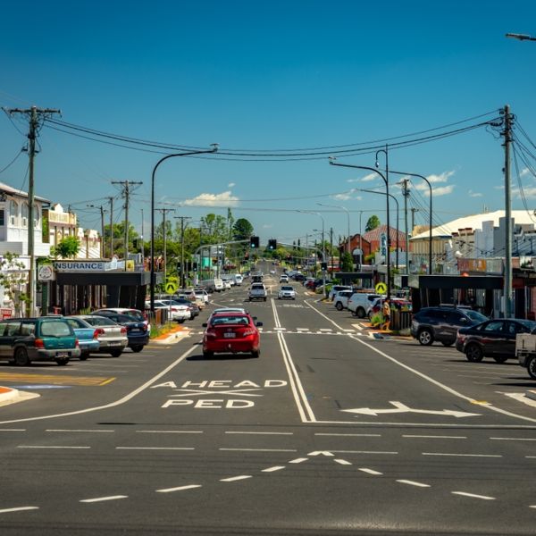 A street view of a suburban Australian street with car traffic and overhead power lines